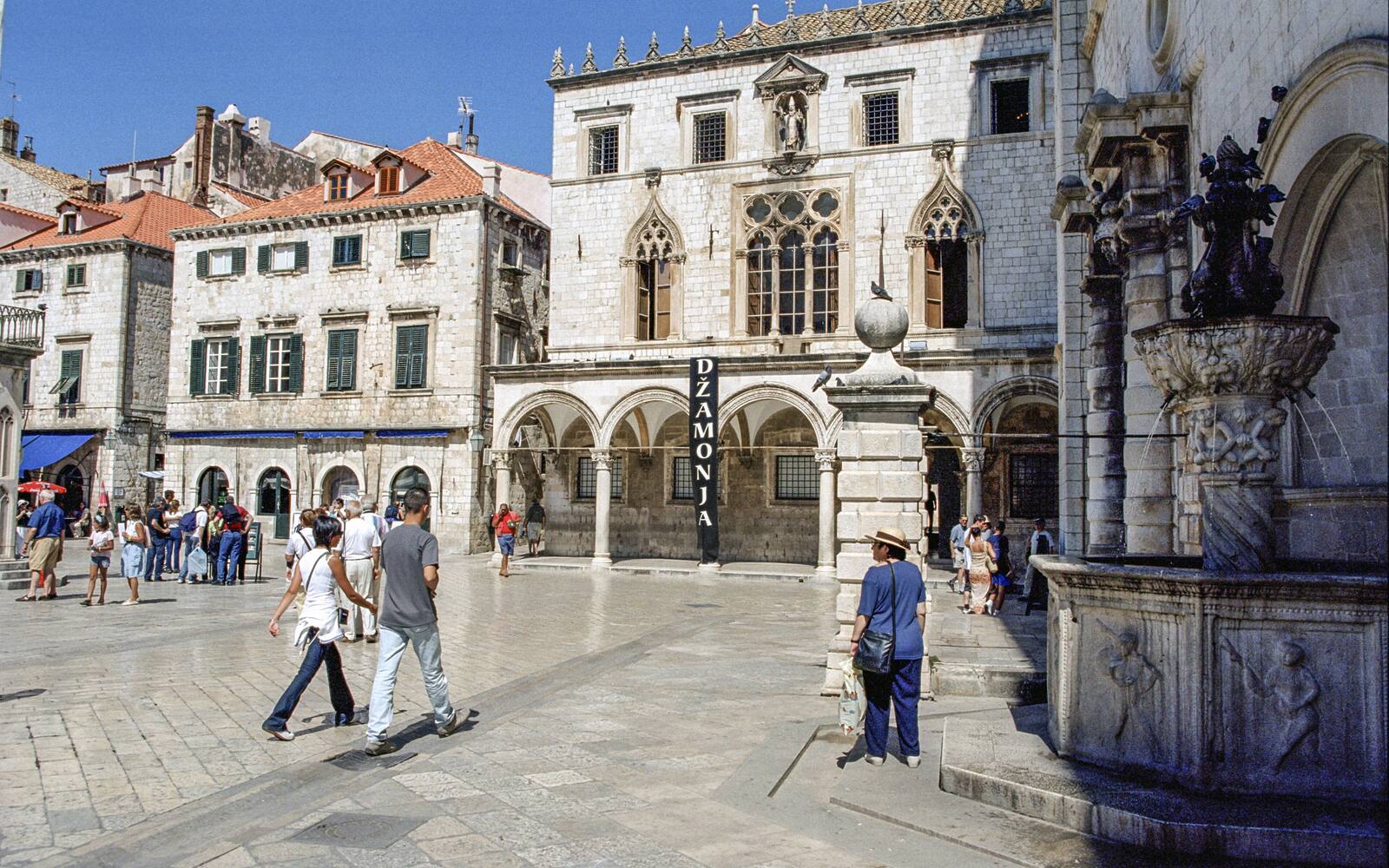 De Stradun in Dubrovnik met het Sponzapaleis en wandelaars op de glanzende kalkstenen straat