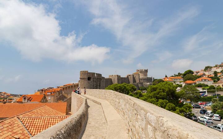 Wandelpad over de stadsmuren van Dubrovnik met oranje daken en een fort op de achtergrond
