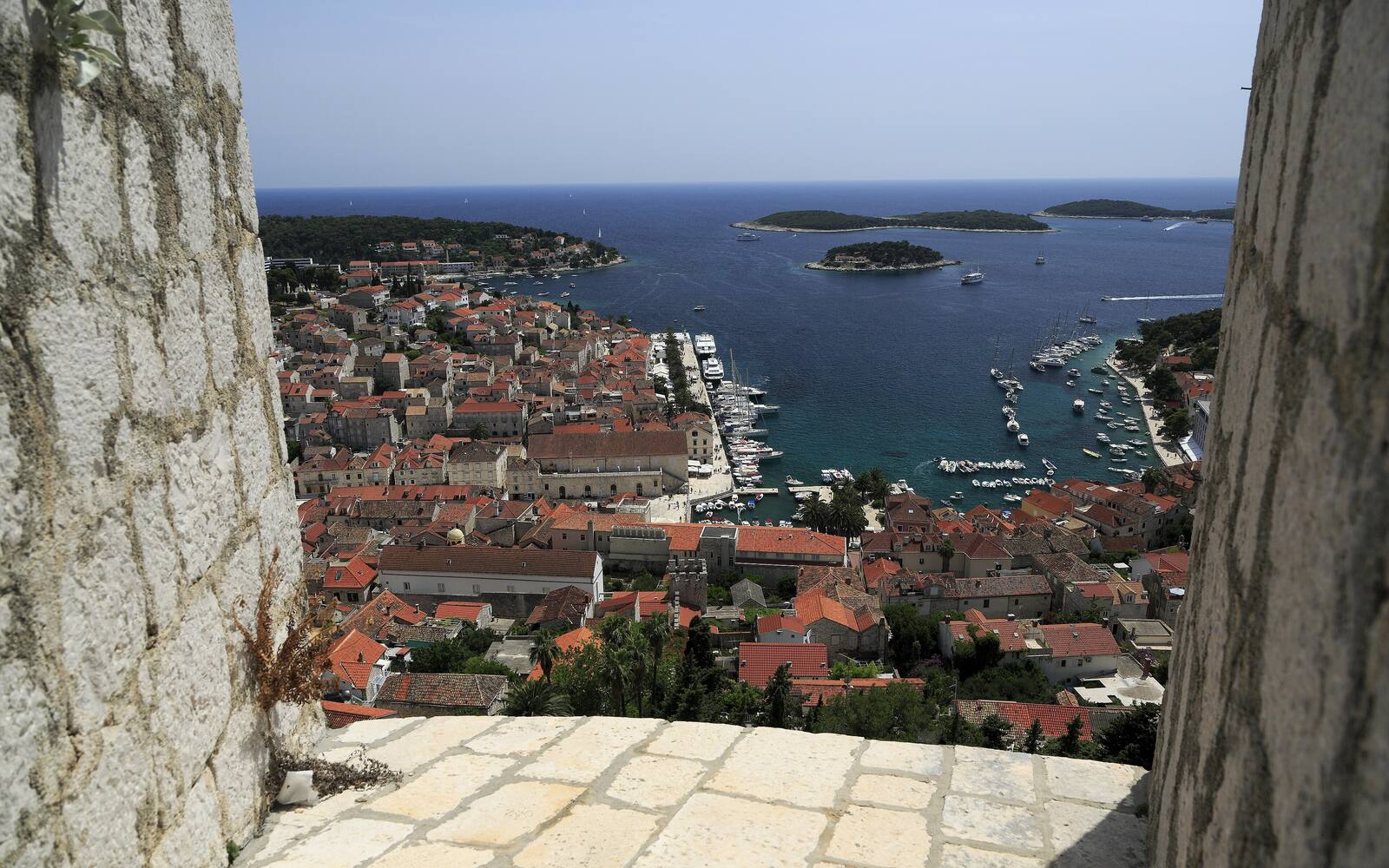Uitzicht vanaf de Fortica over de daken en de haven van Hvar-stad, met de Pakleni-eilanden in zee