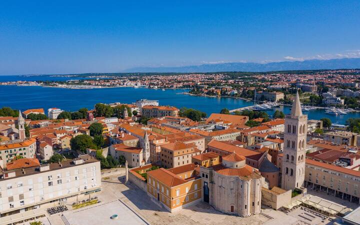 Luchtfoto van de oude stad van Zadar met de ronde Sint-Donatuskerk, het Romeinse forum en de klokkentoren, met de zee op de achtergrond