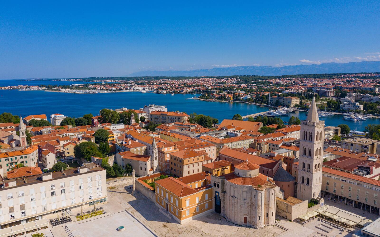 Luchtfoto van de oude stad van Zadar met de ronde Sint-Donatuskerk, het Romeinse forum en de klokkentoren, met de zee op de achtergrond