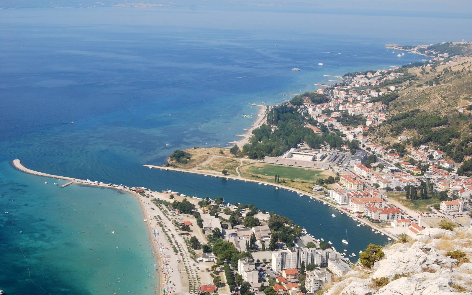 Luchtfoto van Omiš met het lange strand, de pier en de monding van de rivier de Cetina in de Adriatische Zee