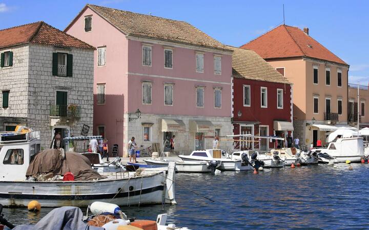 Haven van Stari Grad op Hvar met stenen huizen, cipressen en bootjes in het warme avondlicht