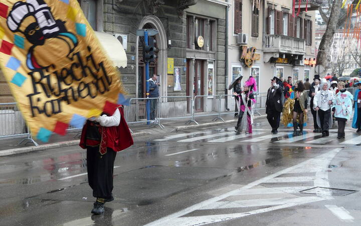 Begin van de carnavalsoptocht in Rijeka, met een vaandeldrager met de vlag van het Riječki karneval en gekostumeerde deelnemers