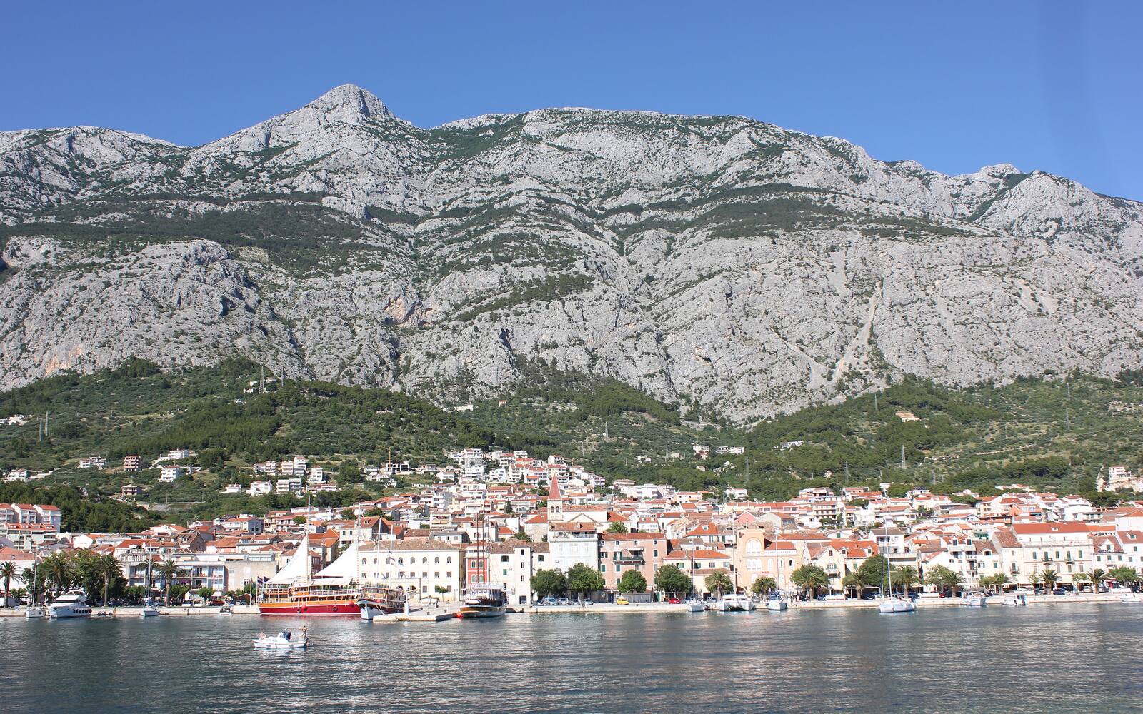 Makarska aan zee met daarachter de kale kalkstenen wanden van het Biokovo-gebergte in Dalmatië