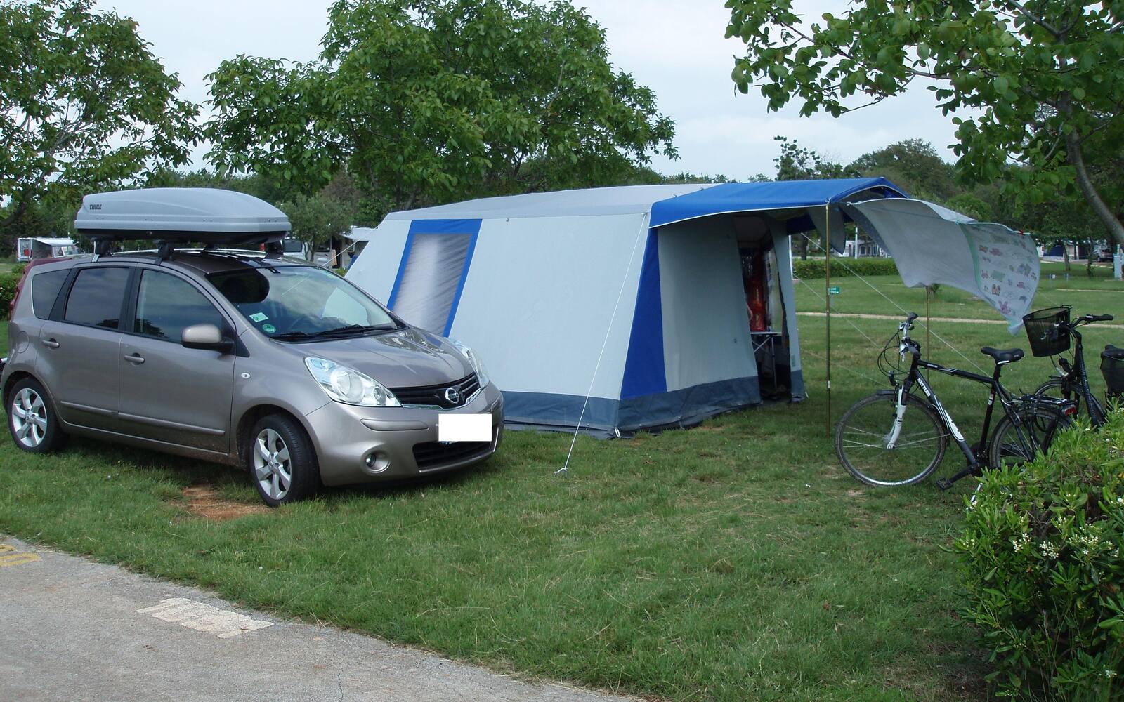 Tent, auto en fietsen op een grasveld van een camping bij Lovrečica in Istrië