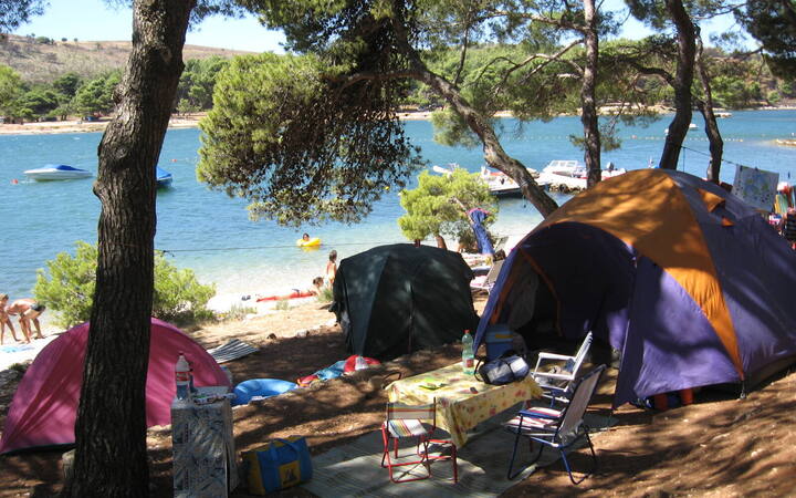 Kleurrijke tenten onder pijnbomen aan een baai op een camping bij Pomer in Istrië