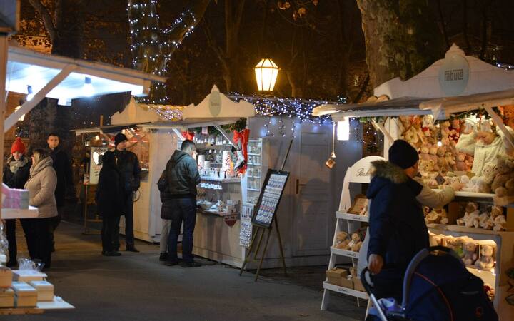 Kraampjes van de adventsmarkt in Zagreb met kerstverlichting en bezoekers in winterjassen