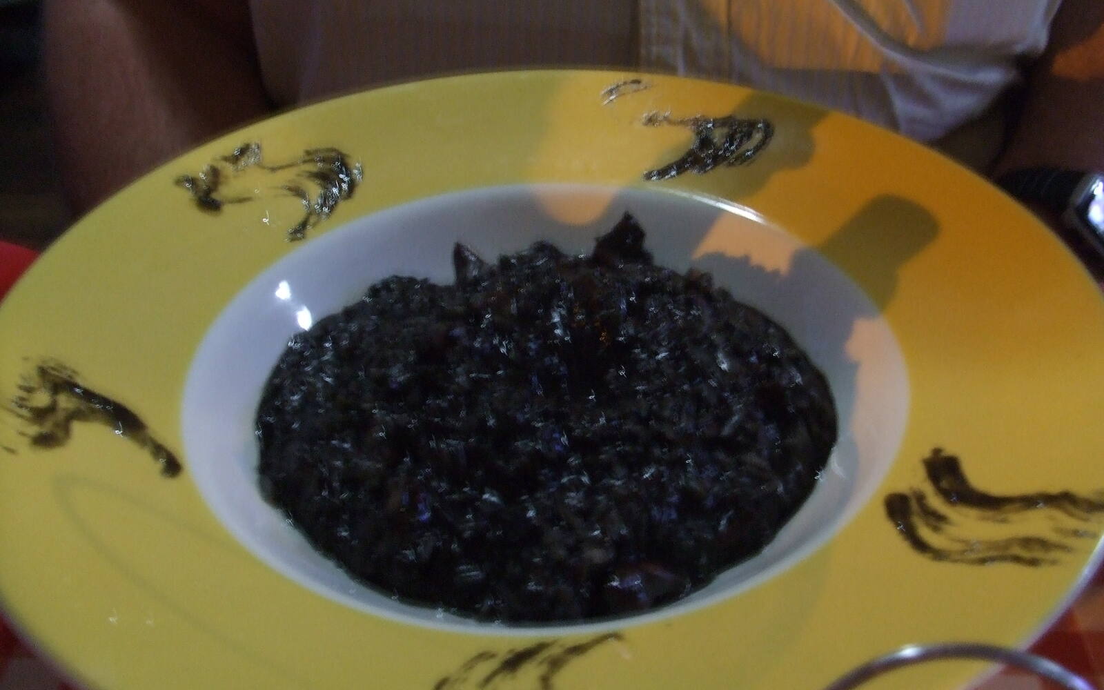 Bord zwarte risotto met inktvisinkt op een geel bord