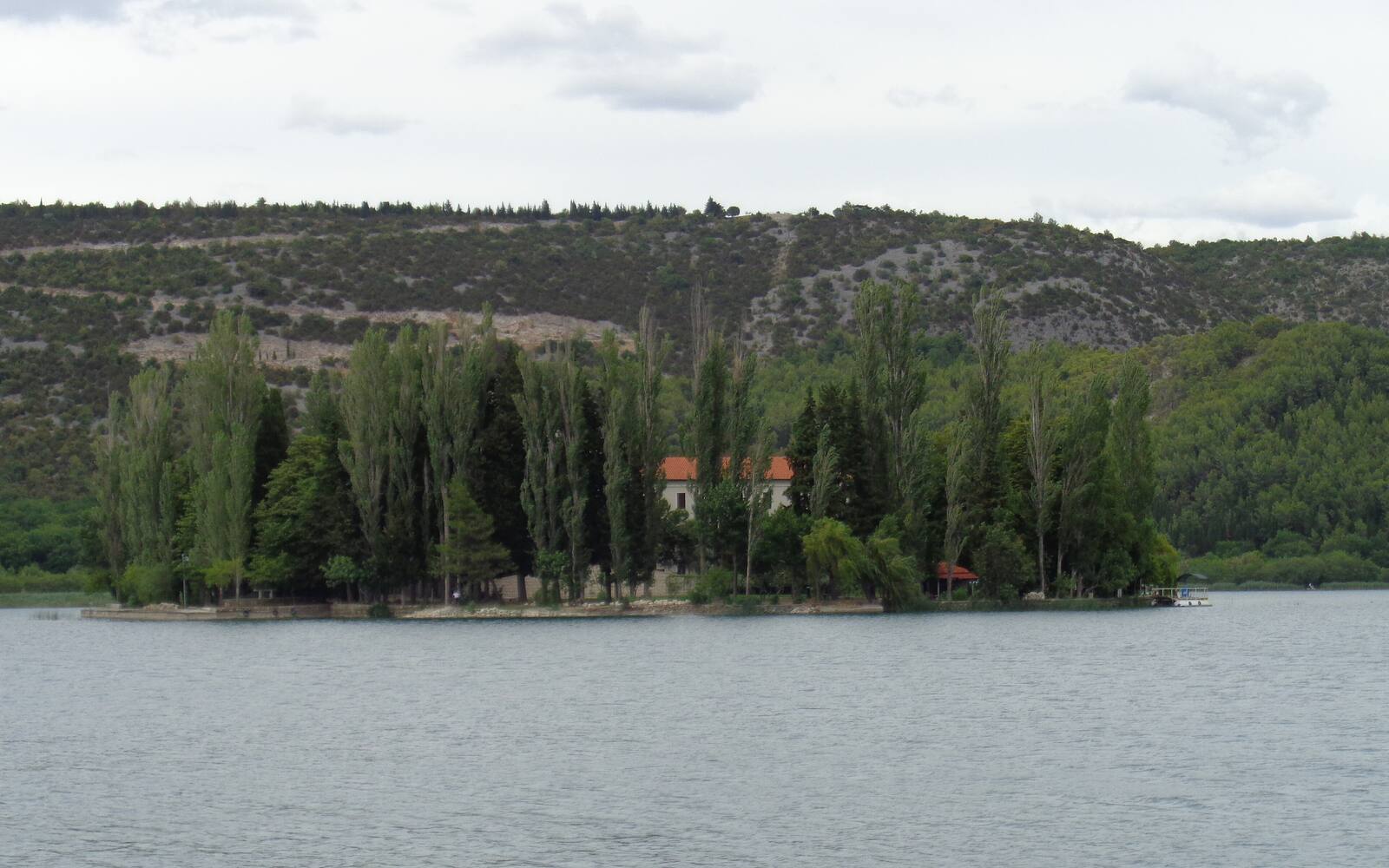 Het eilandje Visovac met franciscanenklooster tussen hoge populieren midden in de Krka