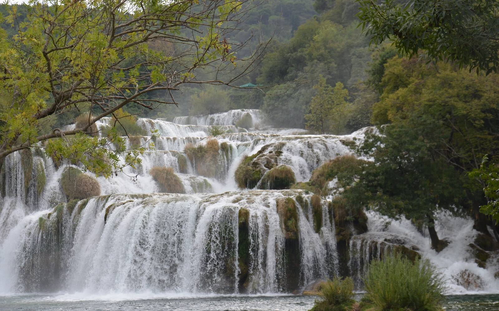 De brede travertijnwatervallen van Skradinski buk in Nationaal Park Krka, omringd door groen