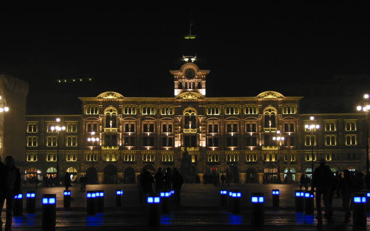 Het verlichte stadhuis aan de Piazza Unità d'Italia in Triëst bij nacht